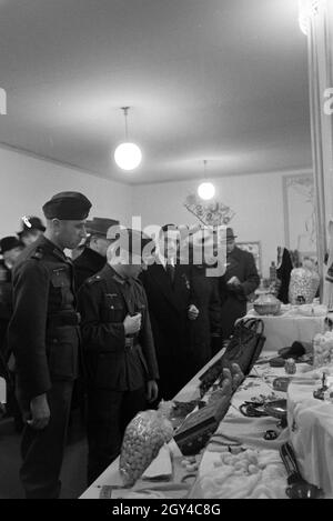 Besucher der Leipziger Frühjahrsmesse vor einem Stand mit Kunsthandwerk; Deutschland 1941. I visitatori della Leipziger Frühjahrsmesse davanti a un cavalletto con artwork; Germania 1941. Foto Stock