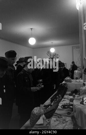 Besucher der Leipziger Frühjahrsmesse vor einem Stand mit Kunsthandwerk; Deutschland 1941. I visitatori della Leipziger Frühjahrsmesse davanti a un cavalletto con artwork; Germania 1941. Foto Stock