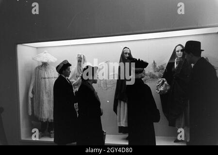 Messebesucher vor einem Schaukasten mit landestypischen Trachten, anlässlich der Wiener Modewoche im Haus der Mode ' Palais Lobkowitz', Deutschland 1940er Jahre. I visitatori di una fiera di fronte a una vetrina con costumi tradizionali, in occasione del Wiener Modewoche nella casa della moda ' Palais Lobkowitz', Germania 1940. Foto Stock