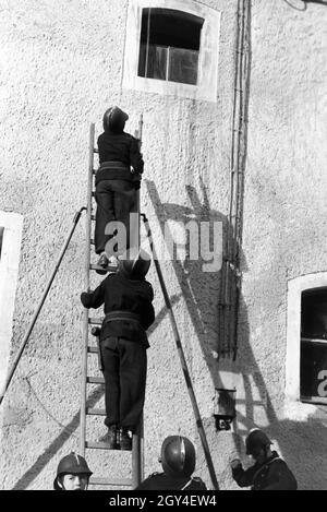 Zwei Jungen von der Kinderfeuerwehr bei einer Feuerwehrübung mit dem Löschschlauch auf einer Leiter, Deutschland 1930er Jahre. Due ragazzi del Junior vigili del fuoco in piedi su una scala con il tubo flessibile di acqua durante un vigile del fuoco di formazione, Germania 1930s. Foto Stock