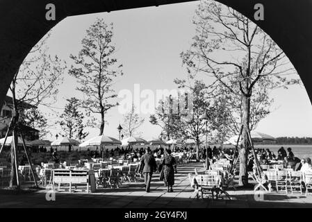 Ansicht der gut besuchten Sonnenterrasse eines cafés am Chiemsee, Deutschland 1930 jahre. Vista sulla terrazza soleggiata di una caffetteria del Chiemsee, Germania anni trenta. Foto Stock