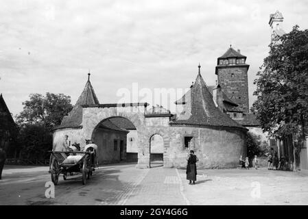 Eine Pferdekutsche beladene fährt durch das Burgtor, eines der ältesten Bauwerke in Rothenburg ob der Tauber, Deutschland 1930er Jahre. Caricata una carrozza trainata da cavalli è la guida attraverso il cancello di castello, uno dei più antichi edifici di Rothenburg ob der Tauber, Germania 1930s. Foto Stock