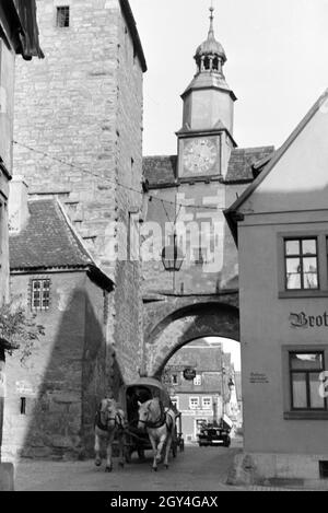 Eine Pferdekutsche fährt durch einen der zahlreichen Turmbögen a Rothenburg ob der Tauber, Deutschland 1930er Jahre. Una carrozza trainata da cavalli è la guida attraverso uno dei molti archi di gate a Rothenburg ob der Tauber, Germania 1930s. Foto Stock