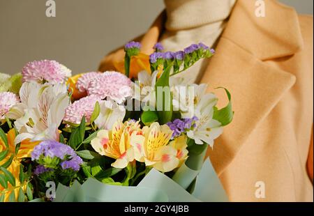 Una donna in un cappotto beige tiene in mano un bel bouquet autunnale. Colore cammello cappotto. Concetto di depersonalizzazione. Primo piano. Foto Stock