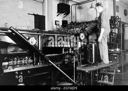 Ein Arbeiter kontrolliert die Rotationsdruckmaschine in den Werken des Maschinenbaukonzerns MAN (Maschinenfabrik Augsburg-Nürnberg), Deutschland 1930er Jahre. Un lavoratore controllando la stampa rotativa premere negli impianti di ingegneria meccanica azienda MAN (Maschinenfabrik Augsburg-Nürnberg), Germania 1930s. Foto Stock