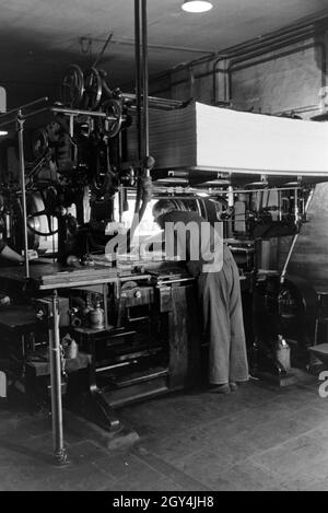 Ein Drucker setzt letteran zu einem Schriftstatz un einer Rotationsdruckmaschine zusammen, Deutschland 1930er Jahre. Una stampante è disporre di tipo metallico ordina rotative da stampa, Germania 1930s. Foto Stock