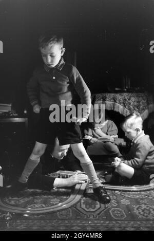 Mitglieder einer kinderreichen Familie spielen im Wohnzimmer, Deutsches Reich 1930er Jahre. I membri di una famiglia estesa a giocare nel soggiorno, Germania 1930s. Foto Stock