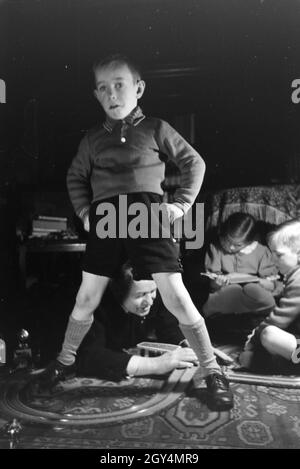 Mitglieder einer kinderreichen Familie spielen im Wohnzimmer, Deutsches Reich 1930er Jahre. I membri di una famiglia estesa a giocare nel soggiorno, Germania 1930s. Foto Stock