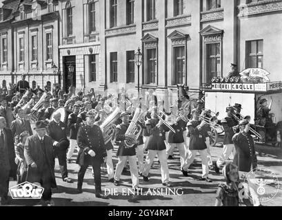 'Nel 1942, Wilhelmstraße a Berlino-Mitte è stato ricostruito negli studi UFA a Babelsberg (allora: Neubabelsberg) per le riprese del film di storia nazista ''The Dismissal''', poiché il vero Wilhelmstraße era già stato segnato da numerose incursioni aeree alleate a Berlino e non poteva più essere utilizzato per riprese storiche esterne. Una banda militare marches attraverso la strada, accompagnato da passanti. La guarnizione del Filmprüfstelle è visibile sul colpo (a destra). [traduzione automatizzata]' Foto Stock