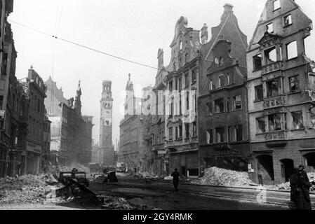 La fotografia mostra Maximilianstraße ad Augusta negli ultimi anni della seconda guerra mondiale. Molte case sono completamente bombardate dopo incursioni aeree. Sullo sfondo si possono vedere il Perlachturm danneggiato e il municipio (a destra). Sul lato destro della foto, tre soldati della Wehrmacht stanno attraversando la strada. [traduzione automatizzata] Foto Stock