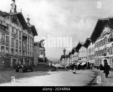 'La foto del 1929 mostra la strada del mercato superiore con la statua di Wenzerer III a Bad Tölz. Di fronte alla statua si trova un'auto con la targa II B (distretto dell'alta Baviera). L'edificio sulla sinistra era il municipio di Bad Tölz a quel tempo (oggi: Museo della città), sul lato destro c'è il ''Bürger Garten''. Sul lato destro della strada ci sono negozi, tra cui (da destra a sinistra): 'tädtische Sparkasse Bad Tölz' e ''Tölzer Zeitung'' nella 'Moralt-Haus' e a ''Bierhalle''. Più in basso si trova il Vecchio Municipio con la sua torre a cipolla. [traduzione automatizzata]' Foto Stock