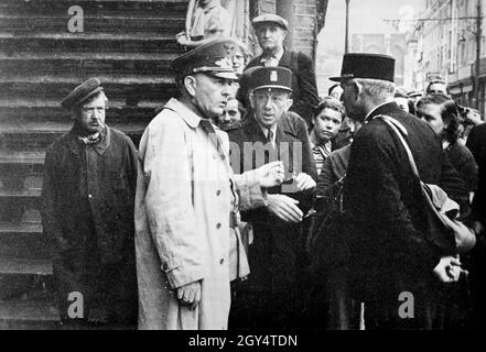 Un funzionario NSV (National Socialist People's Welfare) sta parlando con un uomo. Entrambi sono circondati dalla popolazione civile in attesa della distribuzione di cibo. [traduzione automatizzata] Foto Stock