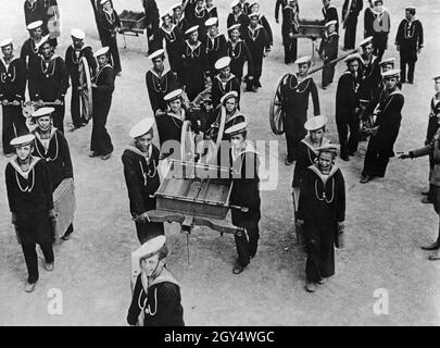 I giovani studenti della scuola navale dell'organizzazione giovanile italiana Opera Nazionale Balilla (i cosiddetti Marinaretti) trasportano le pistole smontate a pezzi da un luogo all'altro durante un esercizio. La fotografia è stata scattata nel 1933, probabilmente nel cortile della Scuola Marinaretti di Roma. [traduzione automatizzata] Foto Stock