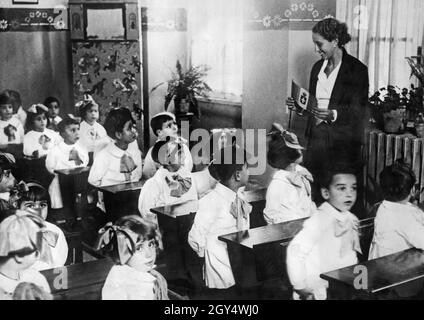 Nell'Italia fascista sono state introdotte uniformi per gli alunni, poi anche per gli insegnanti (circa dal 1934). La foto è stata scattata nel 1934 presso una scuola elementare di Roma e mostra le uniformi scolastiche. L'insegnante sta spiegando la bandiera d'Italia alla sua classe. [traduzione automatizzata] Foto Stock