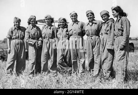 'Questa fotografia, scattata il 20 luglio 1940 nei pressi di Maccarese ad ovest di Roma, mostra un gruppo di giovani donne italiane in abiti da lavoro in un campo raccolto. Sono impiegati in agricoltura come trattori driver durante il raccolto, come molti uomini sono in guerra come soldati. Per la propaganda fascista, immagini come questa servivano come prova della 'mobilitazione del lavoro femminile'. [traduzione automatizzata]' Foto Stock