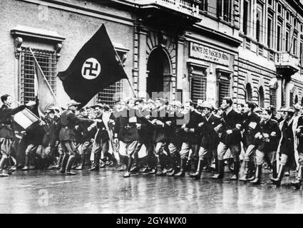 Nel febbraio 1941, pochi mesi dopo che l'Italia entrò in guerra insieme alla Germania nazista alleata, gli studenti fascisti dell'Università di Roma tennero un grande raduno. A questo hanno partecipato studenti che si erano iscritti come volontari di guerra. Le bandiere delle potenze dell'asse sono state portate davanti alla processione. Sullo sfondo, si può vedere un ramo della banca Monte dei Paschi di Siena. [traduzione automatizzata] Foto Stock