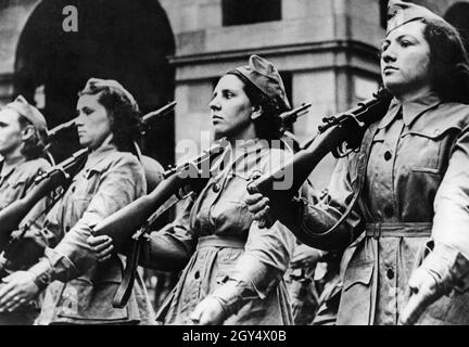 A Roma, il 26 o 27 maggio 1939, di fronte a Mussolini si è svolta una grande sfilata di decine di migliaia di partecipanti fascisti femminili. L'immagine mostra le donne che si accollano i fucili. Accompagnano i loro mariti, soldati coloniali italiani, sulla strada verso le colonie. [traduzione automatizzata] Foto Stock