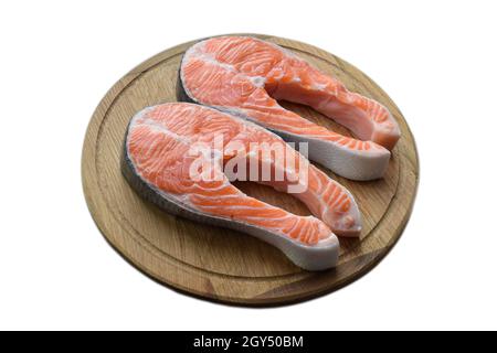 Due bistecche di pesce rosso crudo giacciono su una tavola rotonda di taglio di legno marrone. Su sfondo di ritaglio bianco Foto Stock