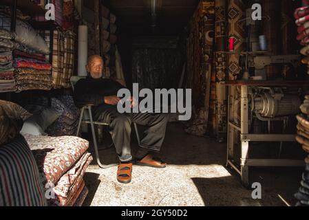 Amman, Giordania - Ottobre 06 2021: Mercato centrale nella capitale Amman, vecchio uomo è il suo negozio di sarto con macchina da cucire e tessuti Foto Stock