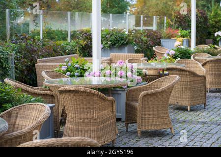 Terrazza vuota all'aperto con mobili in vimini e fiori in vaso per l'intrattenimento estivo Foto Stock