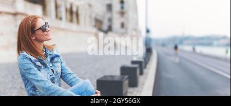 Giovane allegra donna rossa ungherese che si rilassa al palazzo del Parlamento, Budapest, Ungheria Foto Stock