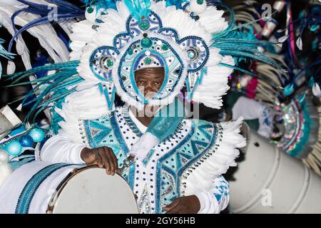 Gente, vestita in costumi, battendo i tamburi mentre celebra Junkanoo nelle strade delle Bahamas Foto Stock