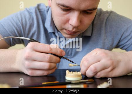 Tecnico dentale modellando le corone dei denti con cera calda. Luogo di lavoro di un tecnico odontoiatrico Foto Stock