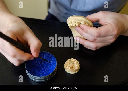 Tecnico dentale modellando le corone dei denti con cera calda. Luogo di lavoro di un tecnico odontoiatrico Foto Stock