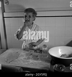 Ein kleiner Junge nascht in der Küche vom Teig für die Weihnachtsplätzchen, Deutschland 1930er Jahre. Un ragazzino di roditura impasto per biscotti di Natale, Germania 1930s. Foto Stock
