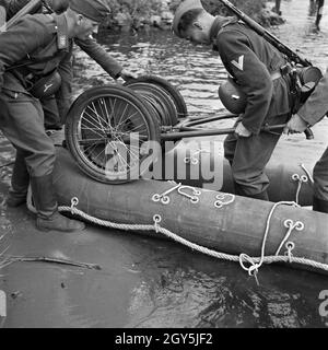 Original-Bildunterschrift: Der Kabelwagen wird auf dem Boot befestigt, Deutschland 1940er Jahre. Il tamburo del cavo viene caricato per la barca in gomma, Germania 1940s. Foto Stock