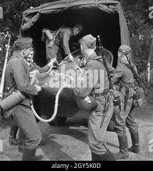 Original-Bildunterschrift: Das Schlauchboot zum Übersetzen einer Kabeltrommel über einen Fluß wird ausgeladen. Mit größter Schnelligkeit wird dadurch die Kabellegung durchgeführt, Deutschland 1940er Jahre. Una barca di gomma è preso da un camion per assicurare una veloce posa di cavi, Germania 1940s. Foto Stock