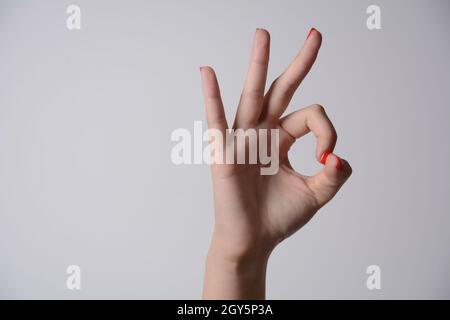 Mano della donna ok segno su sfondo bianco. Foto Stock