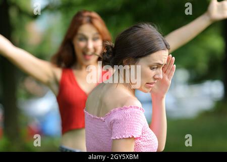 Donna stressata evitando di incontrare il suo amico che cammina in un parco Foto Stock