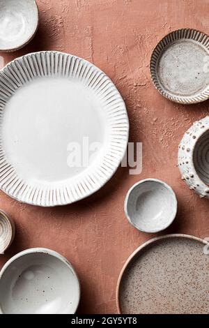Una vista dall'alto di una varietà di ceramiche neutre sparate su uno sfondo di terracotta Foto Stock
