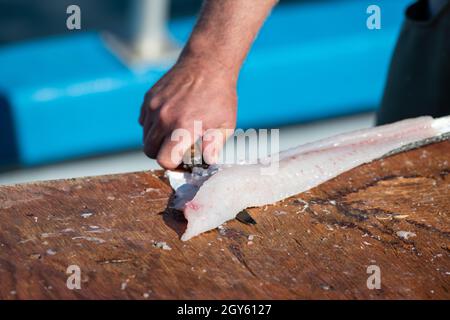 Pesce bianco fresco, merluzzo ripieno e pulito su un tavolo in un ristorante. Lo chef prepara il pesce fresco per il mercato. Ci sono dei filetti di raccordo,. Foto Stock