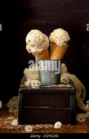 Due coni per cialde che tengono delle cucchiai di gelato al cocco. Foto Stock