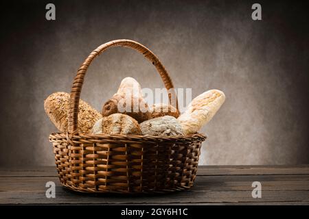 assortimento di pane al forno in cestino di vimini su tavola di legno Foto Stock
