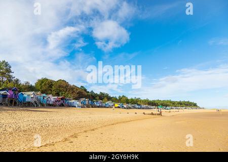 Row of Beach Huts con vista sulla baia di Holkham a Wells-Next-the-Sea sulla costa nord del Norfolk in una mattinata di ottobre luminosa e soleggiata con People Walking Foto Stock