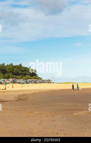 Famosa Row of Beach Huts che sovrastano Holkham Bay a Wells-Next-the-Sea sulla costa nord del Norfolk in una luminosa e soleggiata mattinata di ottobre con People W. Foto Stock