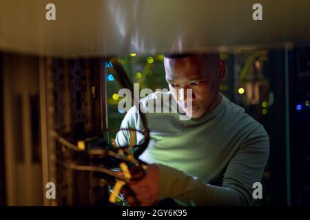 Tecnico informatico maschile africano americano che lavora nella sala server Foto Stock