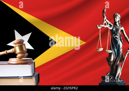 Diritto e giustizia a Timor orientale. Statua di themis e la navata del giudice sullo sfondo della bandiera di Timor Est. Concetto di diritto e giustizia. Foto Stock