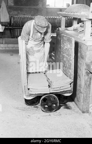 Ein Keramiker der Staatlichen Porzellanmanufaktur Berlin sortiert rohe Keramikplatten für den Schrühbrand, Deutschland 1930er Jahre. Un ceramisti di stato manifattura di porcellana Berlin ordina materie di piastre in ceramica per il bisque cottura, Germania 1930s. Foto Stock