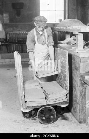 Ein Keramiker der Staatlichen Porzellanmanufaktur Berlin sortiert rohe Keramikplatten für den Schrühbrand, Deutschland 1930er Jahre. Un ceramisti di stato manifattura di porcellana Berlin ordina materie di piastre in ceramica per il bisque cottura, Germania 1930s. Foto Stock