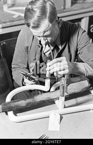 Ein Mitarbeiter einer Leuchtröhrenfabrik bei der Herstellung einer Leuchtöhre, Deutschland 1930er Jahre. Un membro dello staff di produzione di un tubo fluorescente, Germania 1930s. Foto Stock