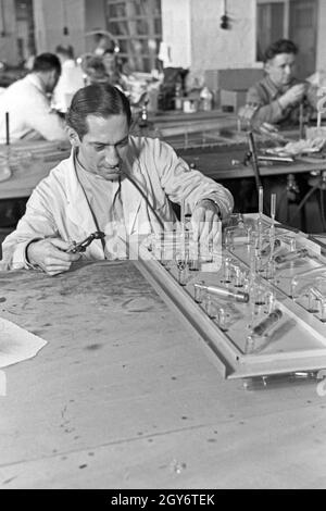 Ein Mitarbeiter einer Leuchtröhrenfabrik bei der Herstellung einer Leuchtöhre, Deutschland 1930er Jahre. Un membro dello staff di produzione di un tubo fluorescente, Germania 1930s. Foto Stock