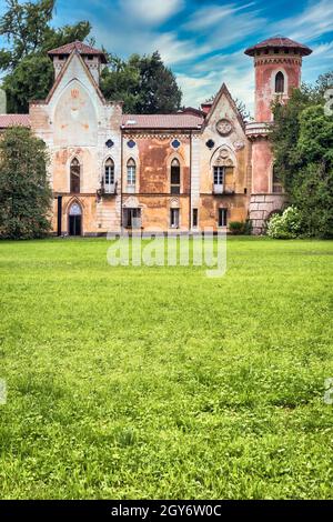 ITALIA, MIRADOLO - CIRCA AGOSTO 2020: Castello di design gotico situato in un giardino all'italiana, pieno di mistero, con luce del tramonto. Foto Stock