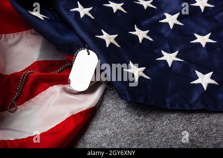 America Stati Uniti bandiera e catena di tag cane, simboli militari, studio girato su cemento bordo sfondo, US Veterans o Independence Day concetto Foto Stock