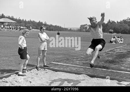 Übung im Weitsprung auf dem Sportplatz des KdF Sportheim Belzig in der Mark Brandenburg, Deutschland 1930er Jahre. Salto in lungo esercizio presso il campo sportivo dello sports club house a Belzig nel Brandeburgo, Germania 1930s. Foto Stock