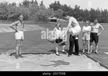 Übung im Weitsprung auf dem Sportplatz des KdF Sportheim Belzig in der Mark Brandenburg, Deutschland 1930er Jahre. Salto in lungo esercizio presso il campo sportivo dello sports club house a Belzig nel Brandeburgo, Germania 1930s. Foto Stock