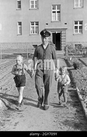 Ein Mann kommt mit zwei kleinen Kindern an der mano aus einem Haus auf der Halbinsel Hela in Ostpreußen, Deutschland 1930er Jahre. Un uomo con due bambini piccoli sulle sue mani che esce di casa a cellule Hela in Prussia orientale, Germania 1930s. Foto Stock